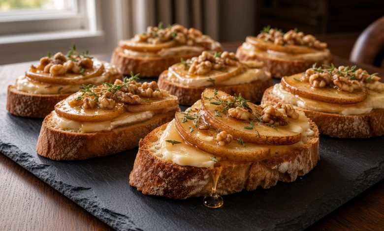 Brie and caramelized pear crostini on a slate board with honey drizzle, walnuts, and fresh thyme