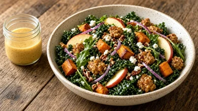 Warm sweet potato sausage salad with kale, apple, pecans, and goat cheese in a wide serving bowl